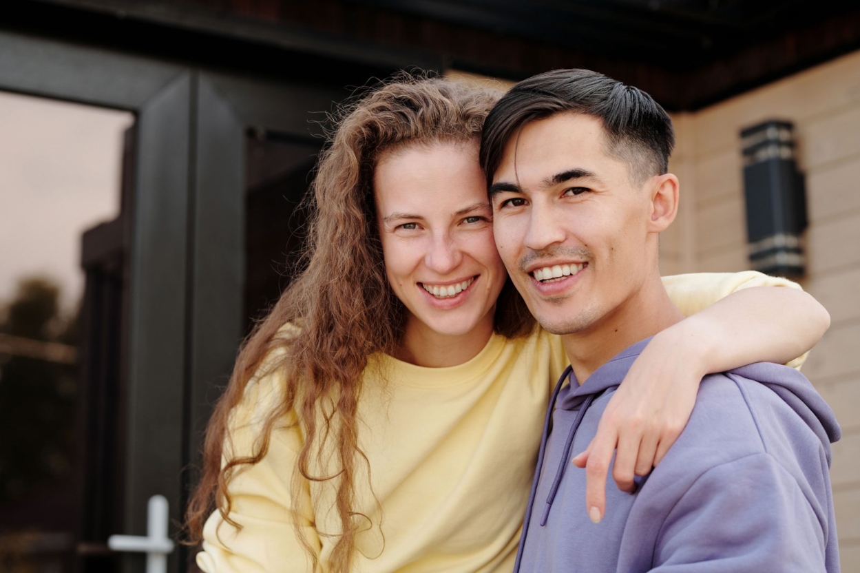 Young couple smiling outdoors in front of a modern home