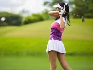 A woman golfer following through on her swing on a sunny fairway