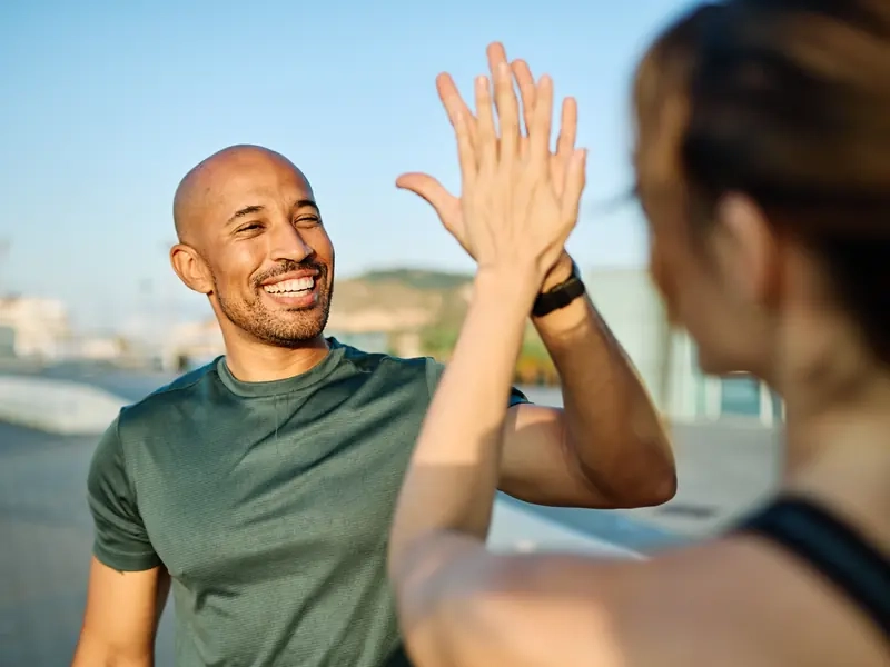 A smiling man high-fiving a woman outdoors after a run