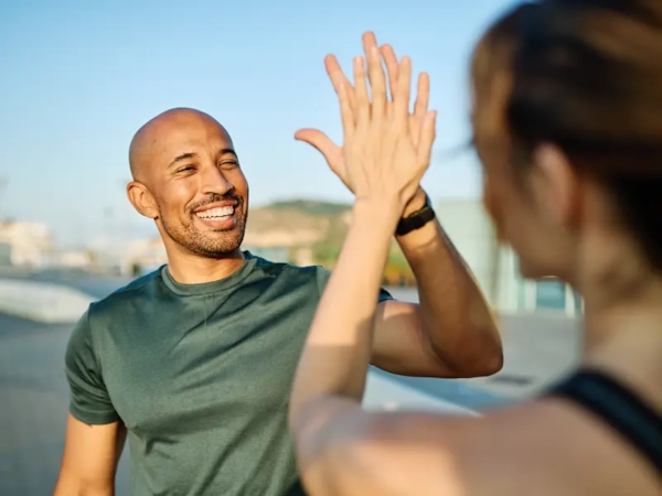 A smiling man high-fiving a woman outdoors after a run