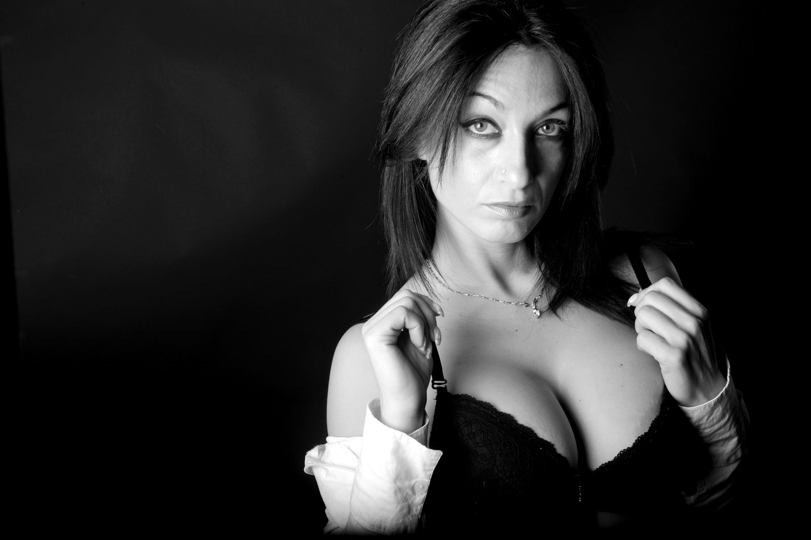 Sensual brunette woman in a black lace bra with an open white shirt