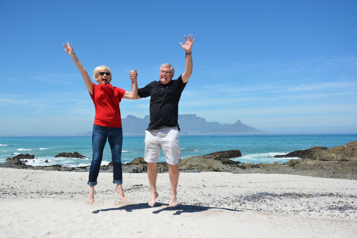Happy older couple jumping together on a sunny beach