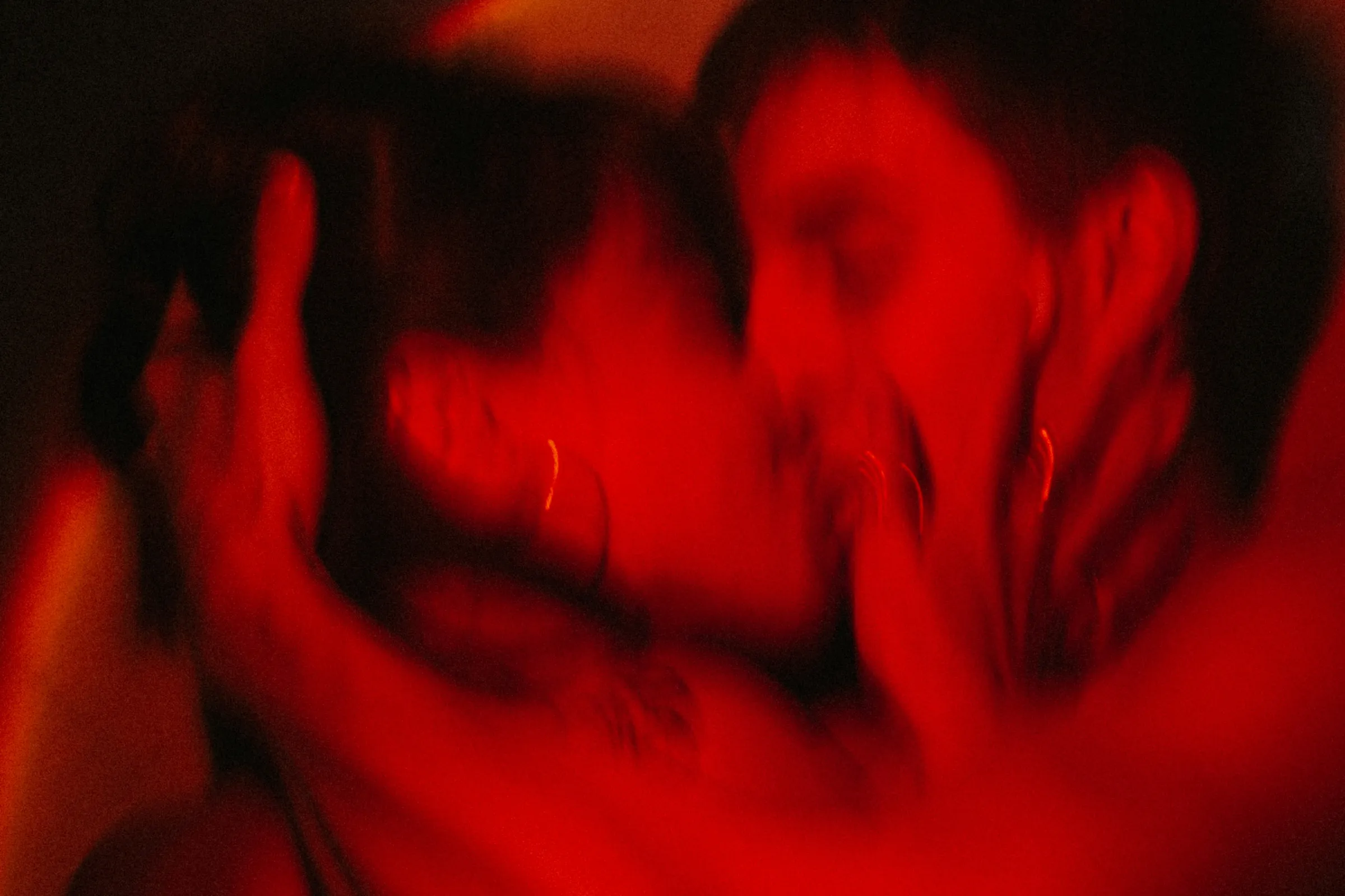 Dos personas besándose bajo una luz roja, captadas en movimiento.