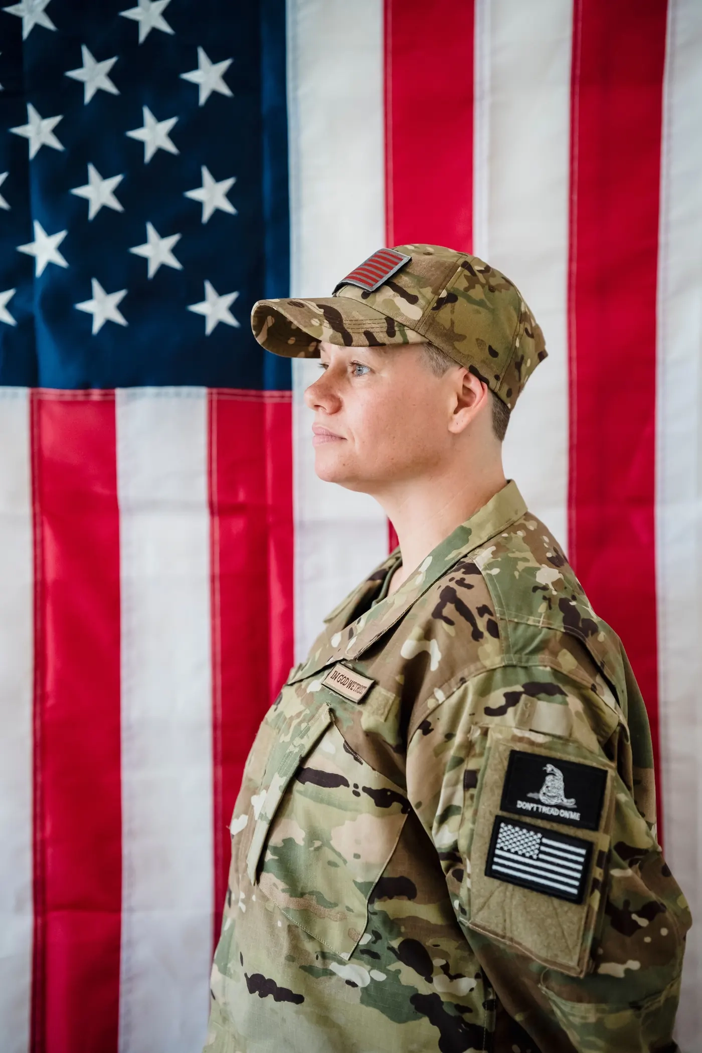 Illustrative portrait of a uniformed service member standing before an American flag