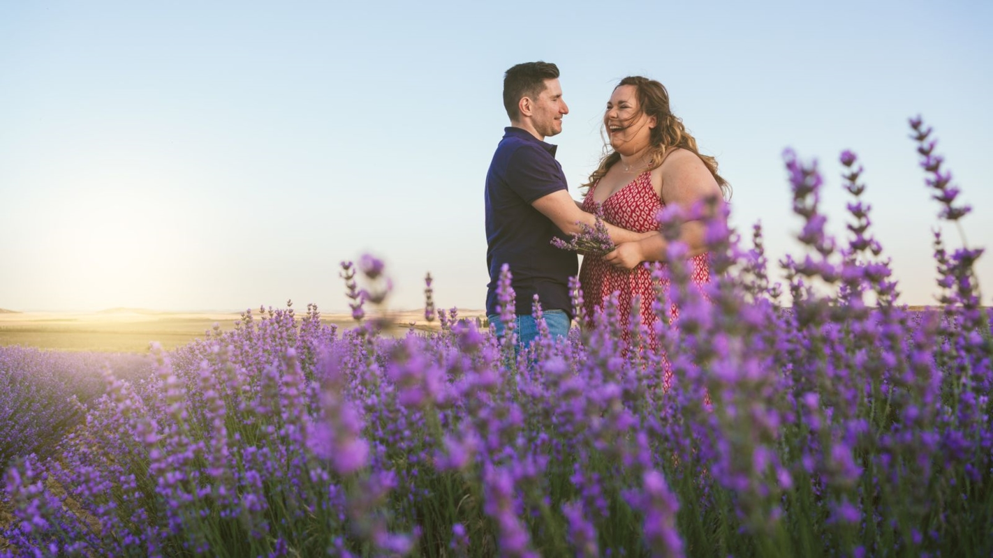 A couple smiling at each other in a lavender field