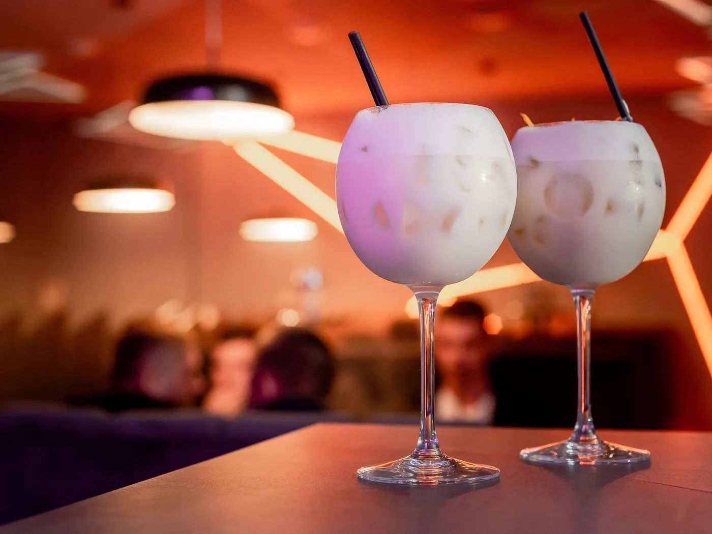Two frosted cocktail glasses side by side on a lounge table under warm orange lights