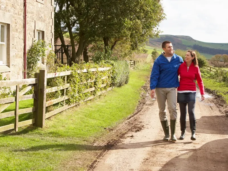 A couple walking a quiet country lane between hedgerows
