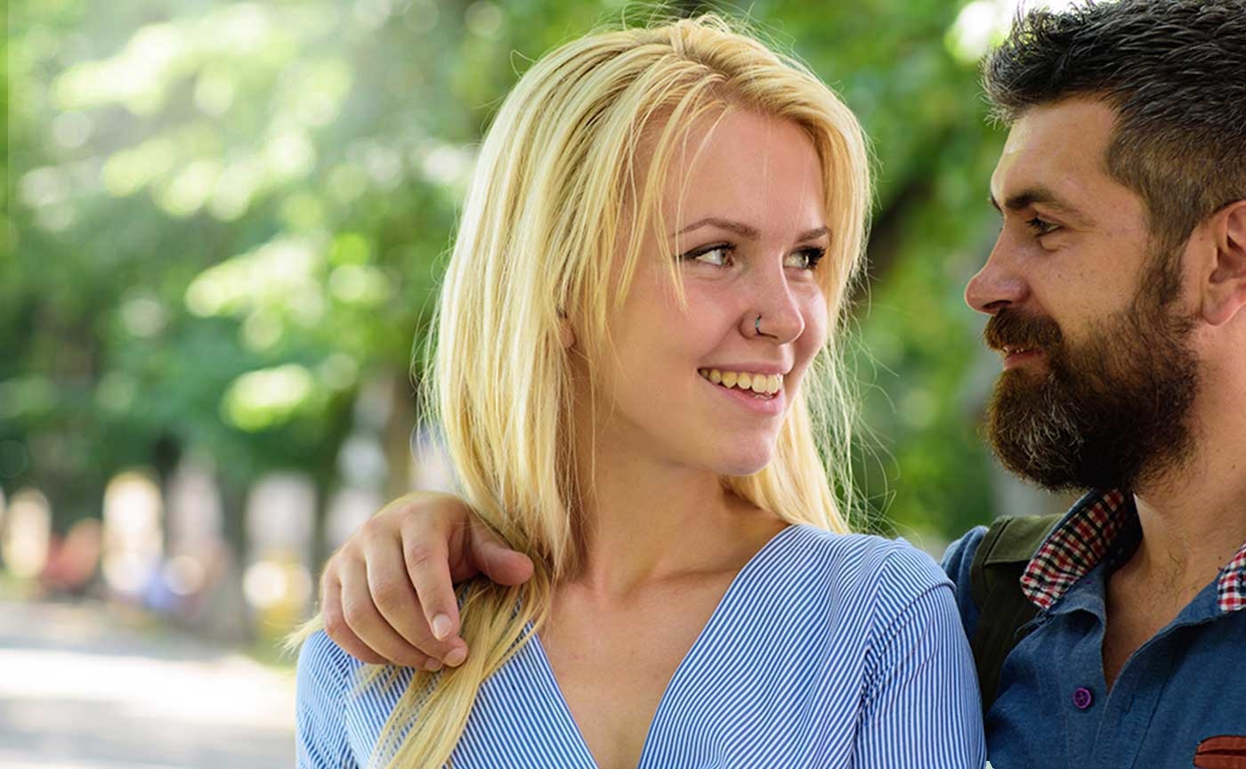 A smiling couple laughing together outdoors