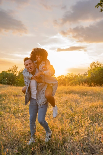 Illustrative photo, not an actual member. A couple laughing together in a sunset field.