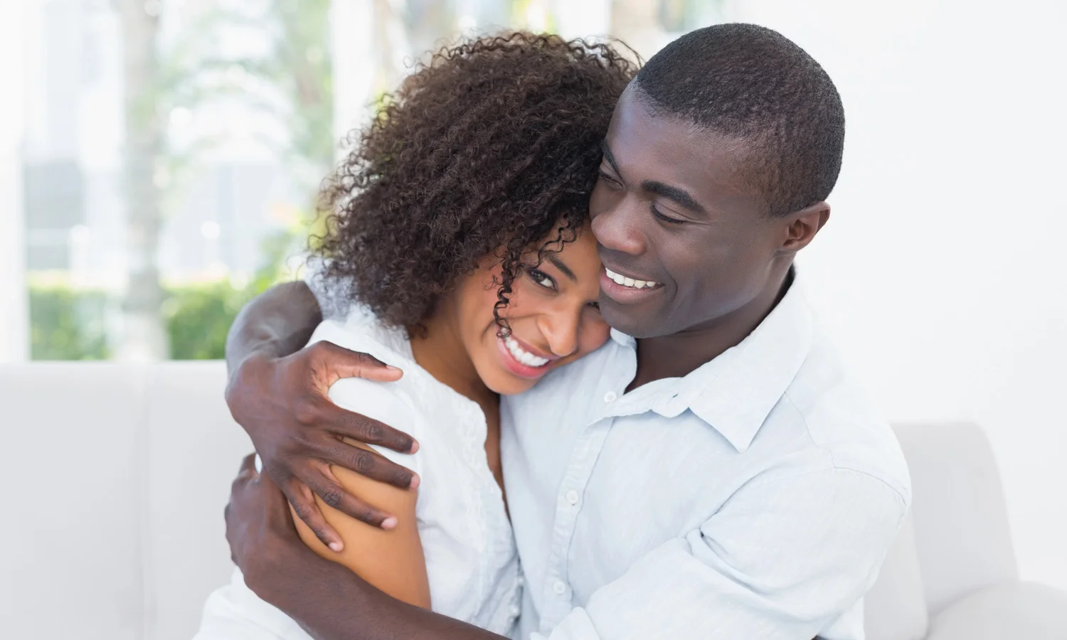A smiling couple embracing on a sofa