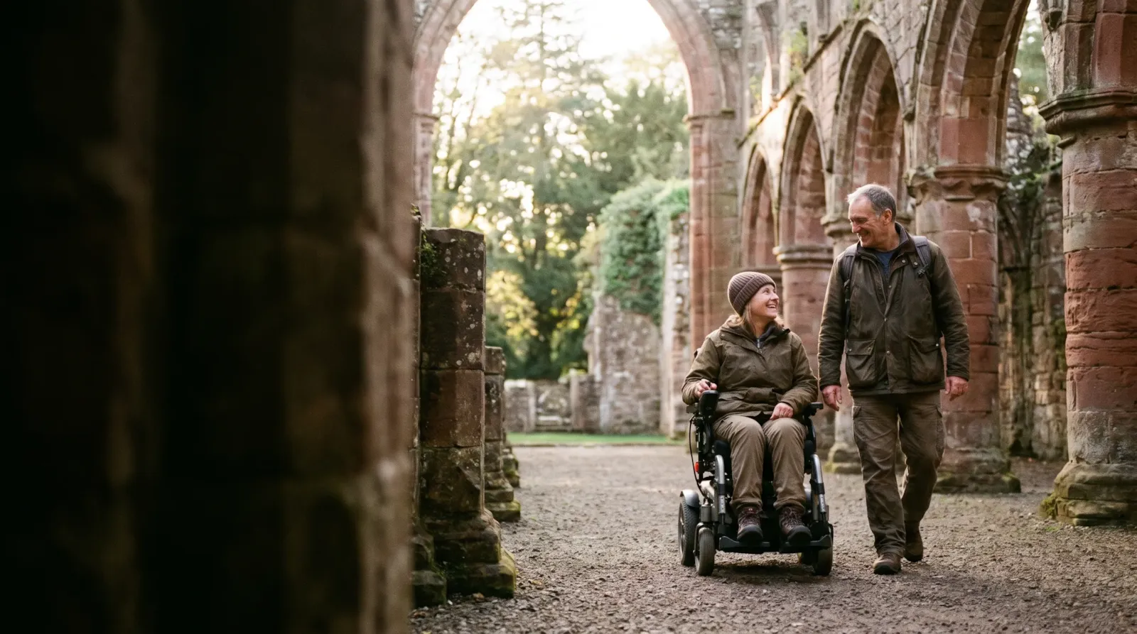 A couple in the grounds of a ruined Borders abbey; the woman uses a powered wheelchair