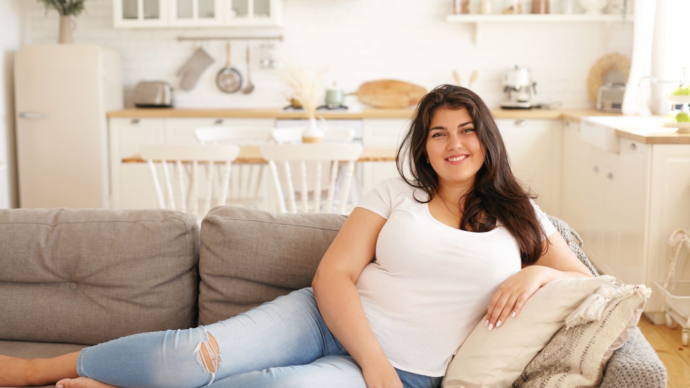 A woman relaxed and smiling on a couch at home