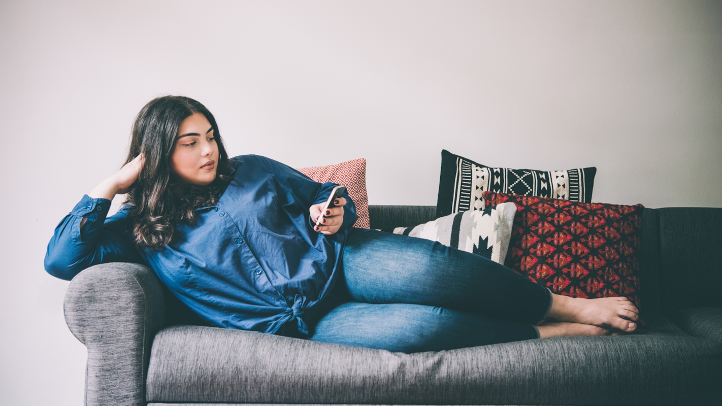 A woman relaxing on the sofa, checking her phone