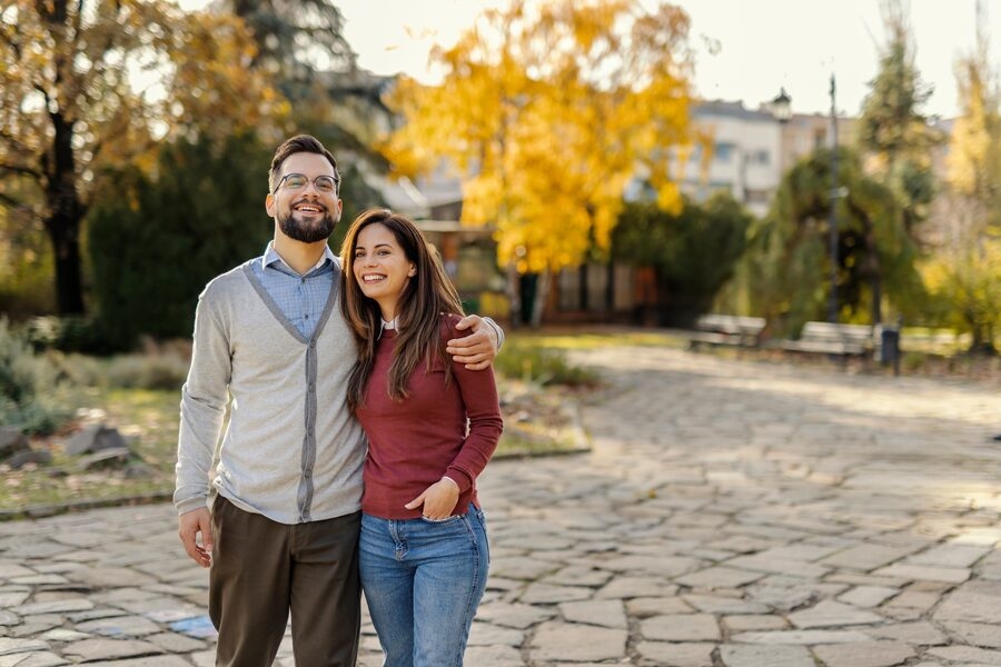 Couple walking together through an autumn park, smiling and relaxed