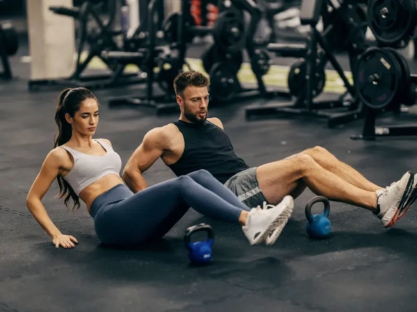 A couple doing a kettlebell core workout together on the gym floor