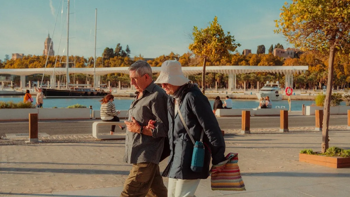 Older couple walking arm in arm along a seaside promenade, illustrative photo of models
