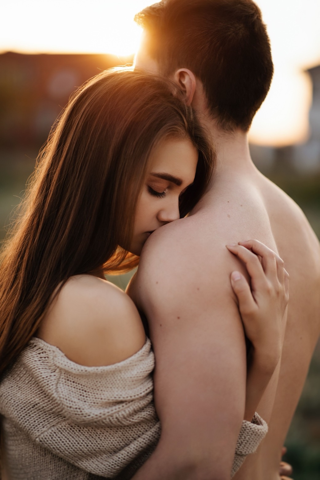 Illustrative stock photo of two adults holding each other in warm evening light. Does not depict real members.