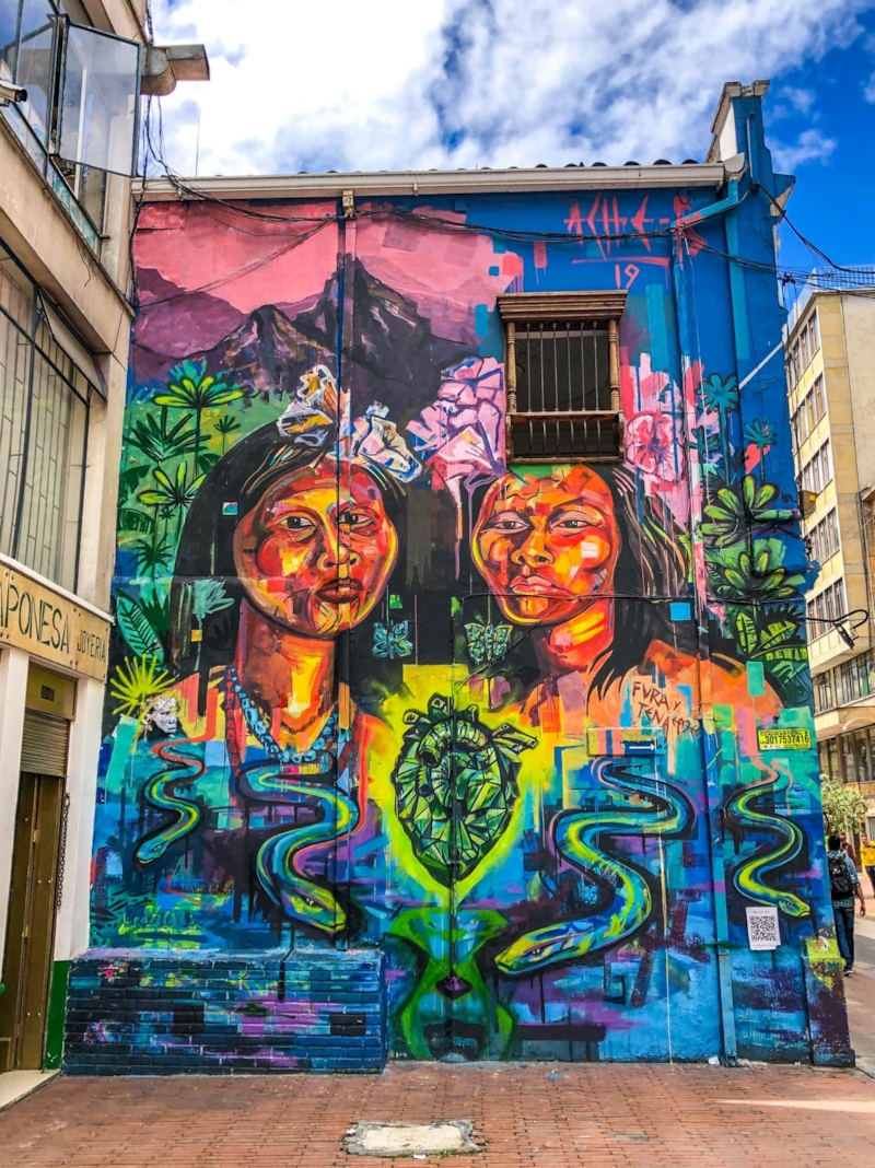 Mural de colores vivos con dos rostros, pintado sobre la fachada de una casa en una calle de Colombia