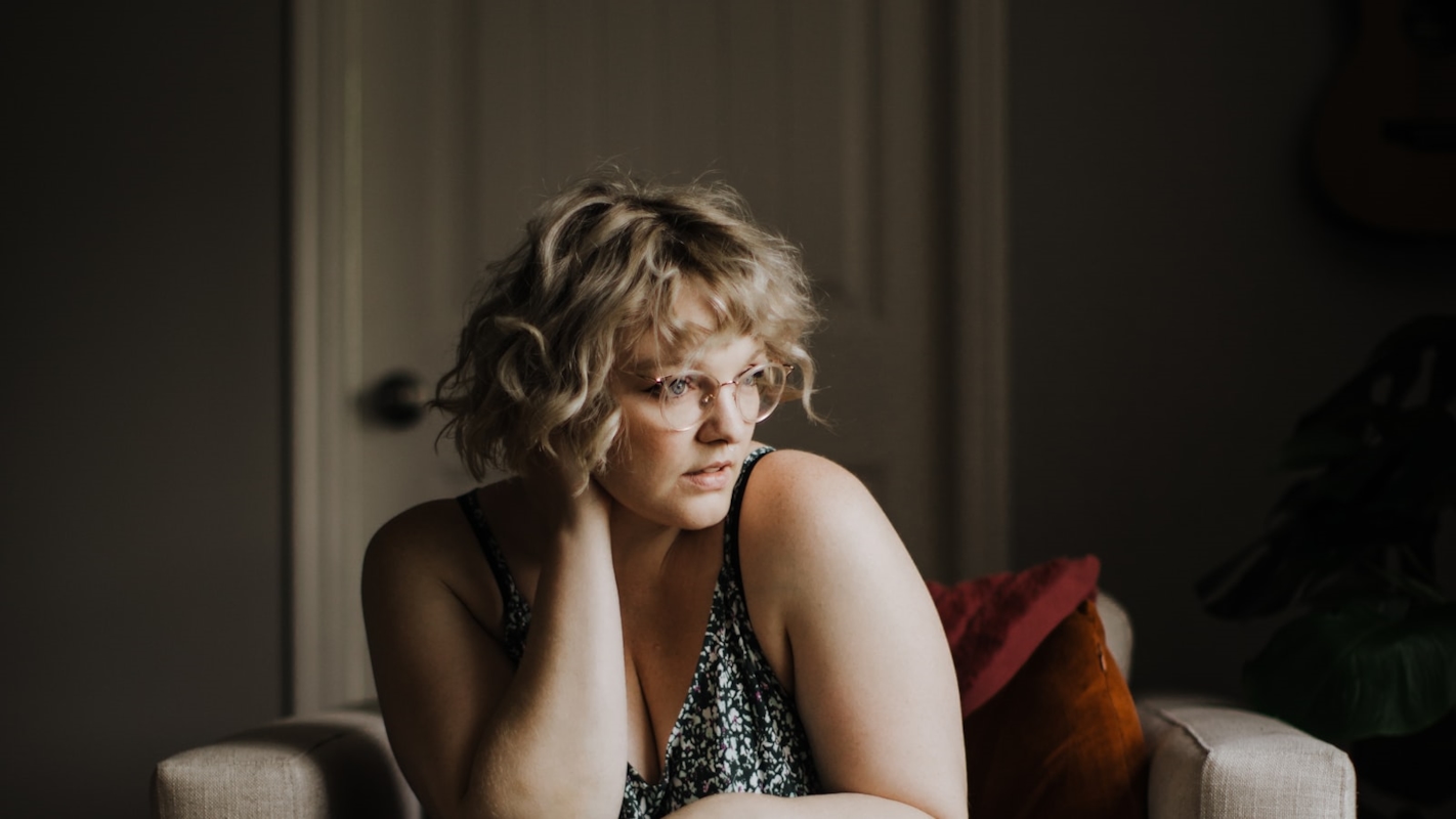 A woman sitting on a couch with a thoughtful, considering expression