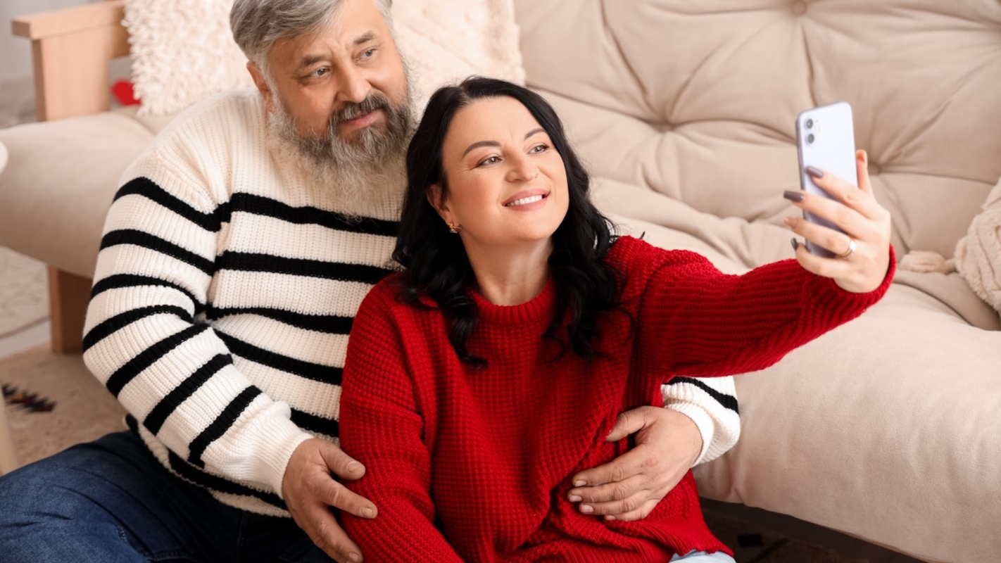 A couple smiling together, taking a selfie on the sofa
