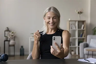 A woman at home delighted by a message on her phone