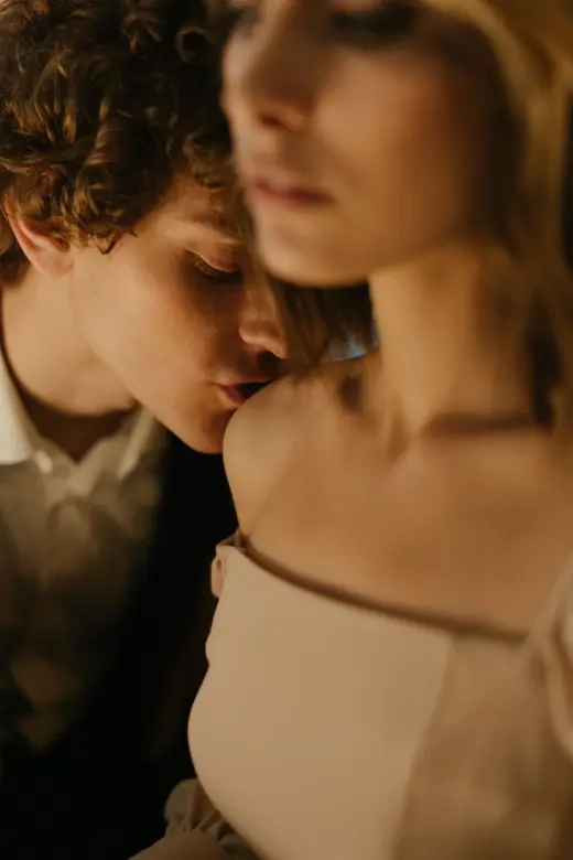 Two people with their faces close together in soft, low light