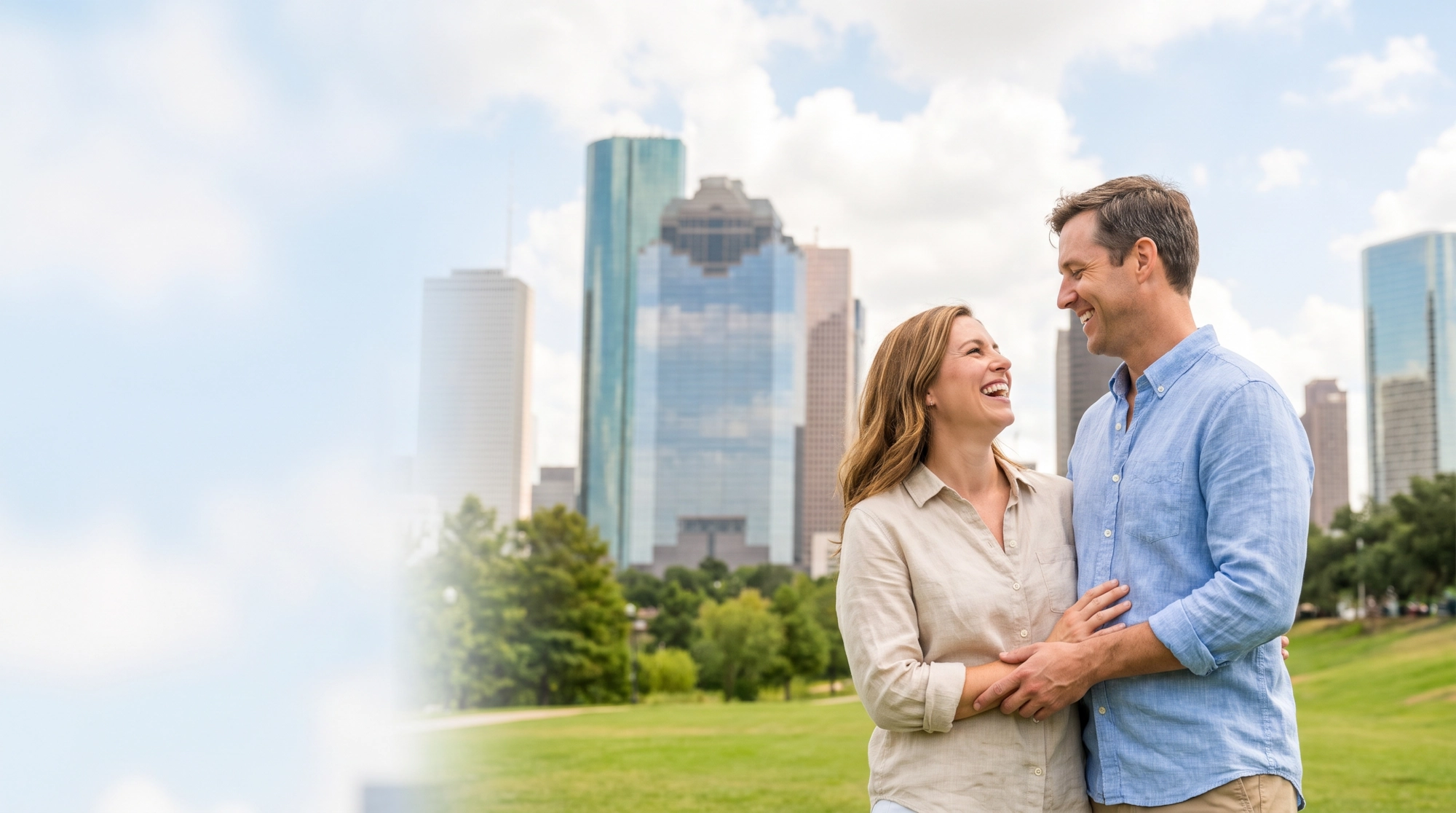 A happy couple laughing together in a Houston park with the downtown skyline behind them