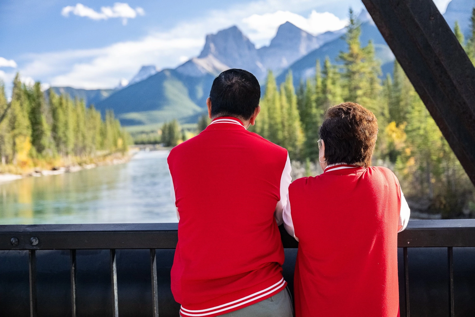 Couple in matching red jackets looking at mountains across a river