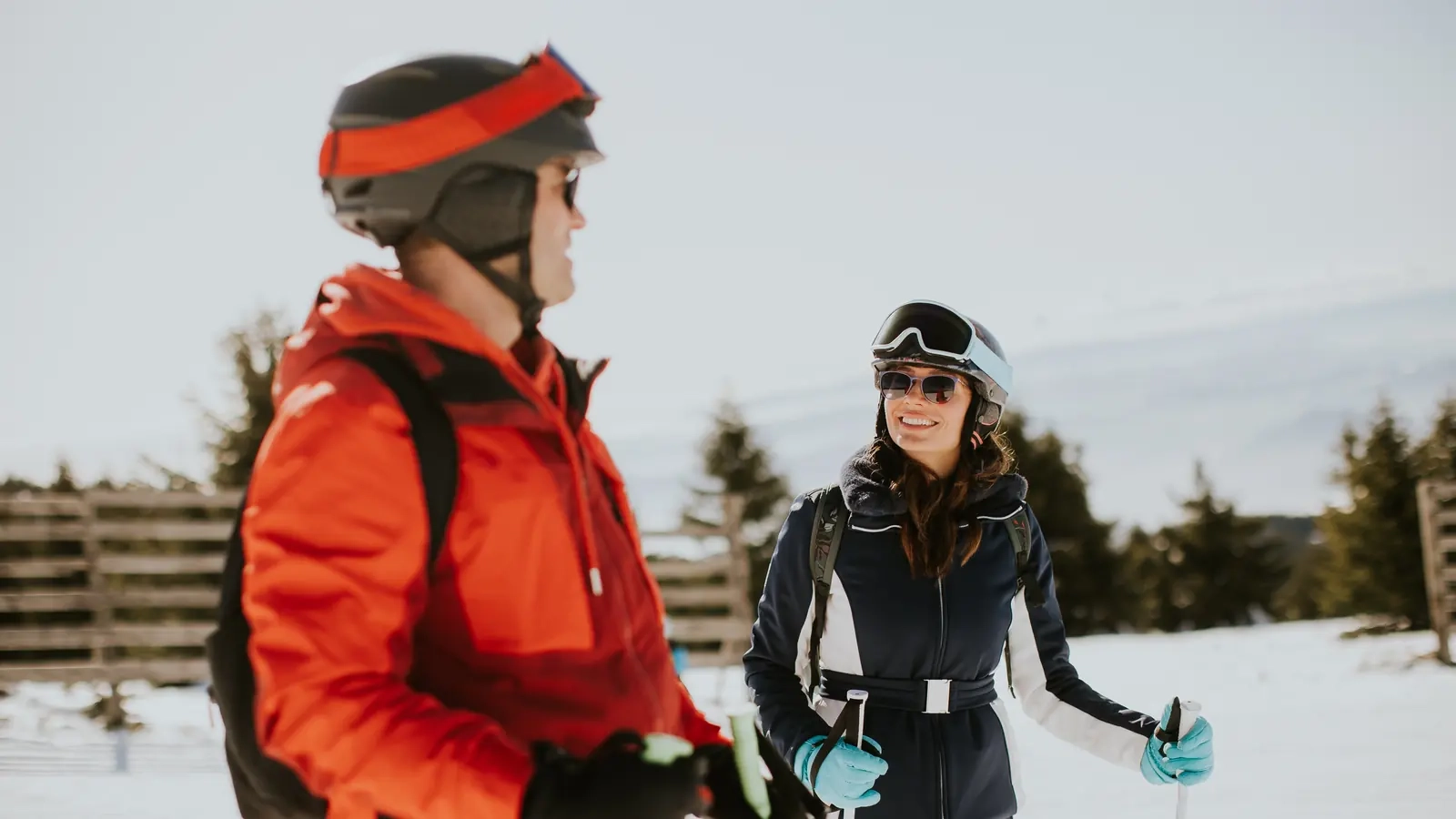 A smiling man and woman in ski gear chatting on a snowy slope
