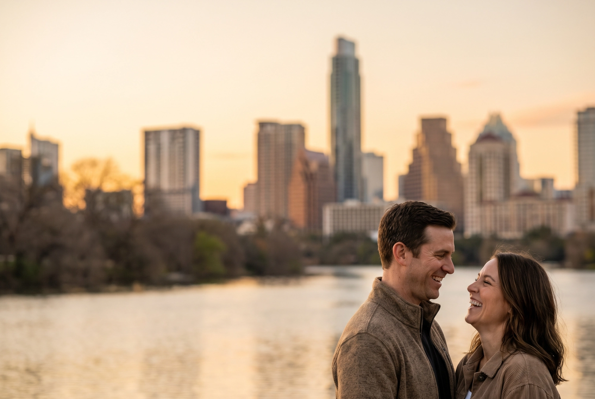 A happy couple smiling together with the downtown Austin skyline across Lady Bird Lake behind them