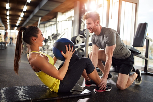 Two fit people spotting each other during a gym session