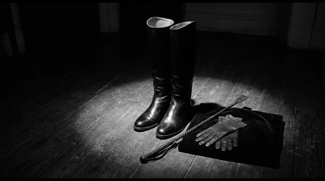 Thigh-high boots, leather gloves and a crop left on the floor under a spotlight
