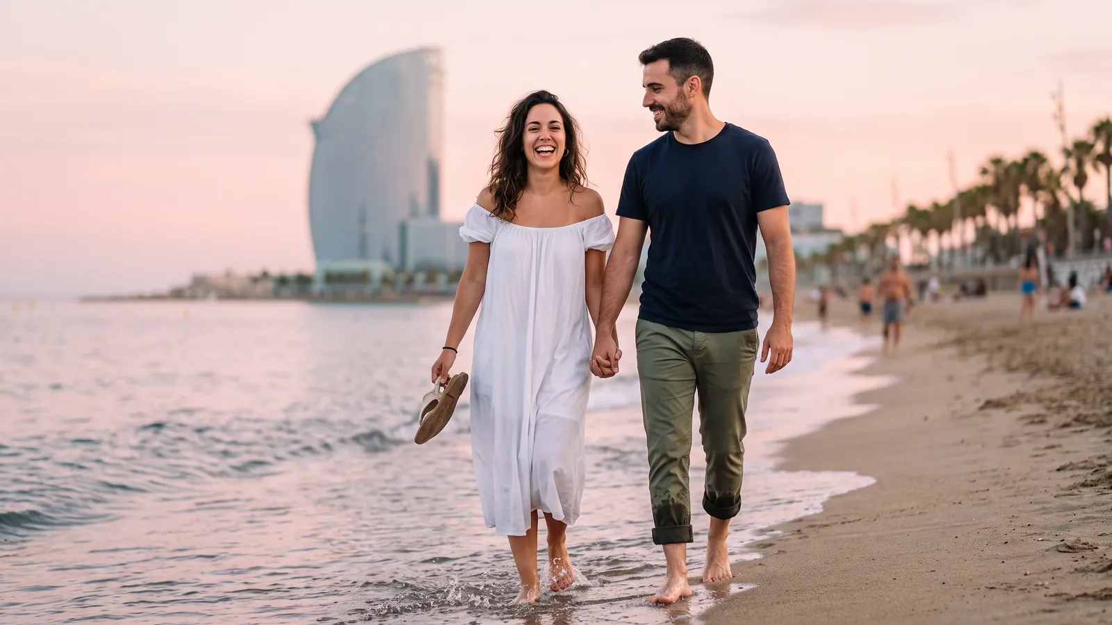 Una pareja descalza camina de la mano por la orilla de la playa de la Barceloneta al anochecer, con el paseo marítimo y las palmeras al fondo (imagen generada por IA)