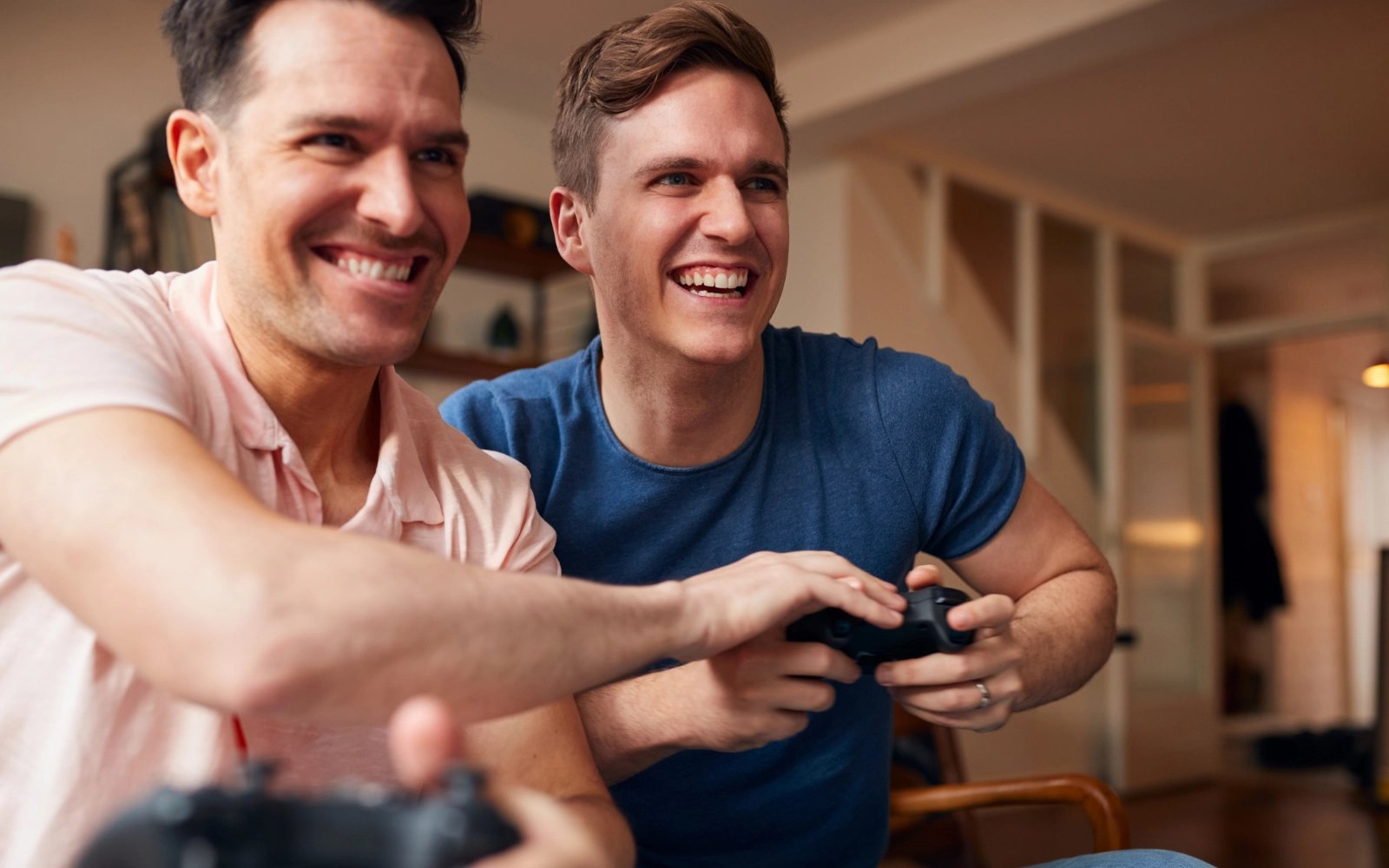 Two men laughing as they play a game with controllers