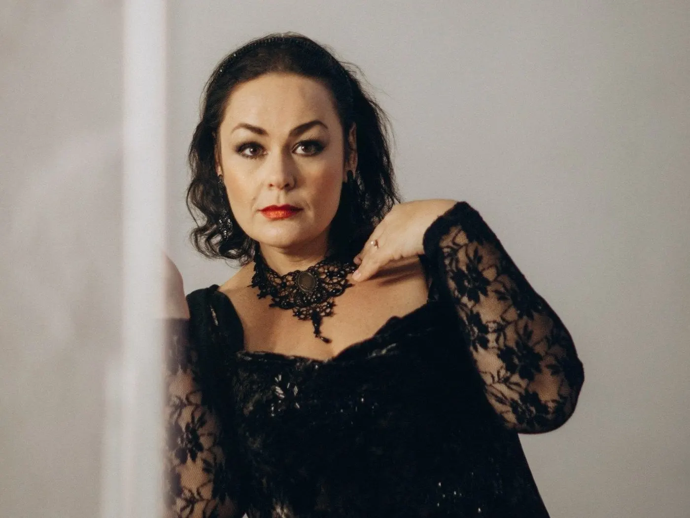 Confident woman in a black lace evening dress and statement lace choker