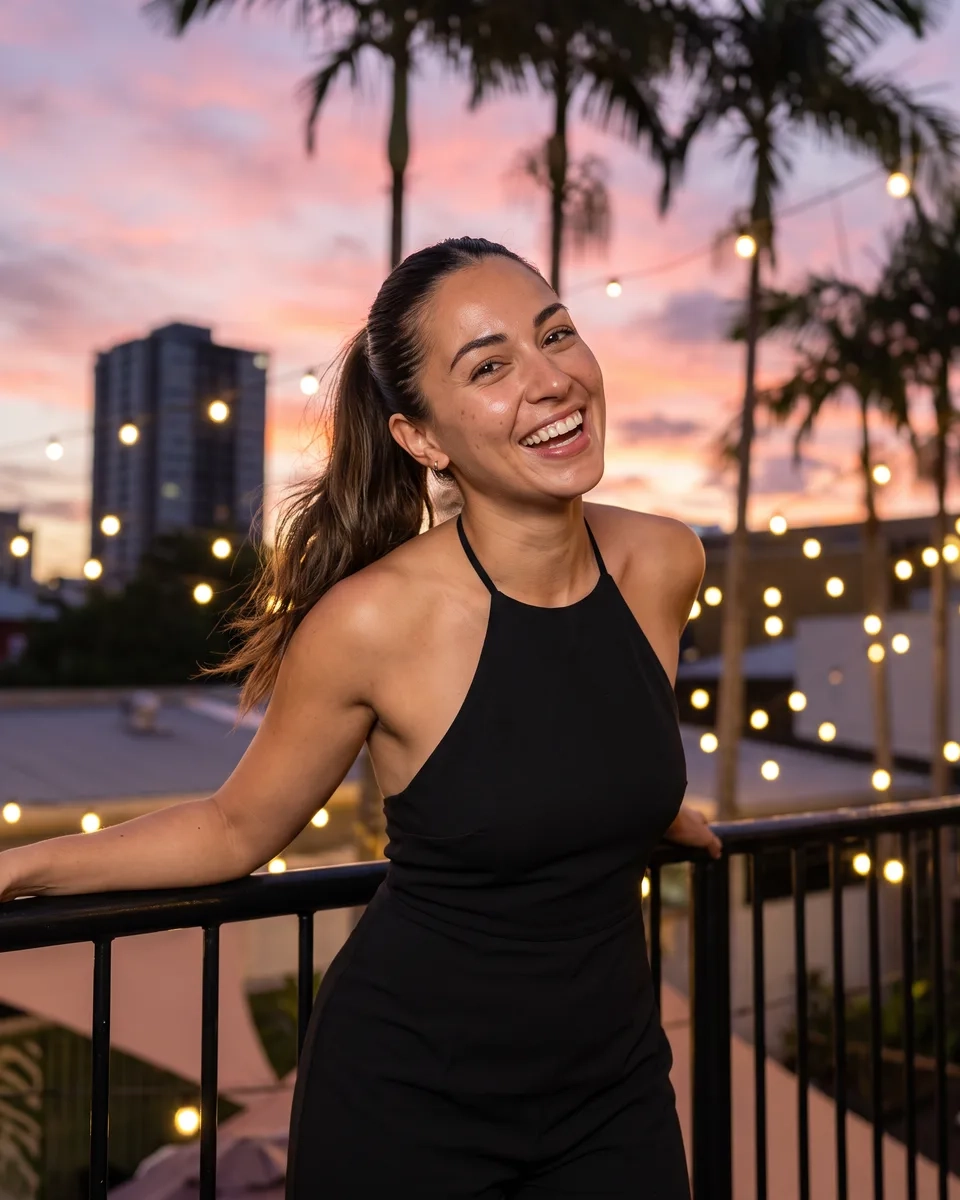 A woman with a sleek dark high ponytail in a black halter-neck jumpsuit laughs against the railing of a rooftop terrace in Fortitude Valley, Brisbane, at dusk (AI-generated image)