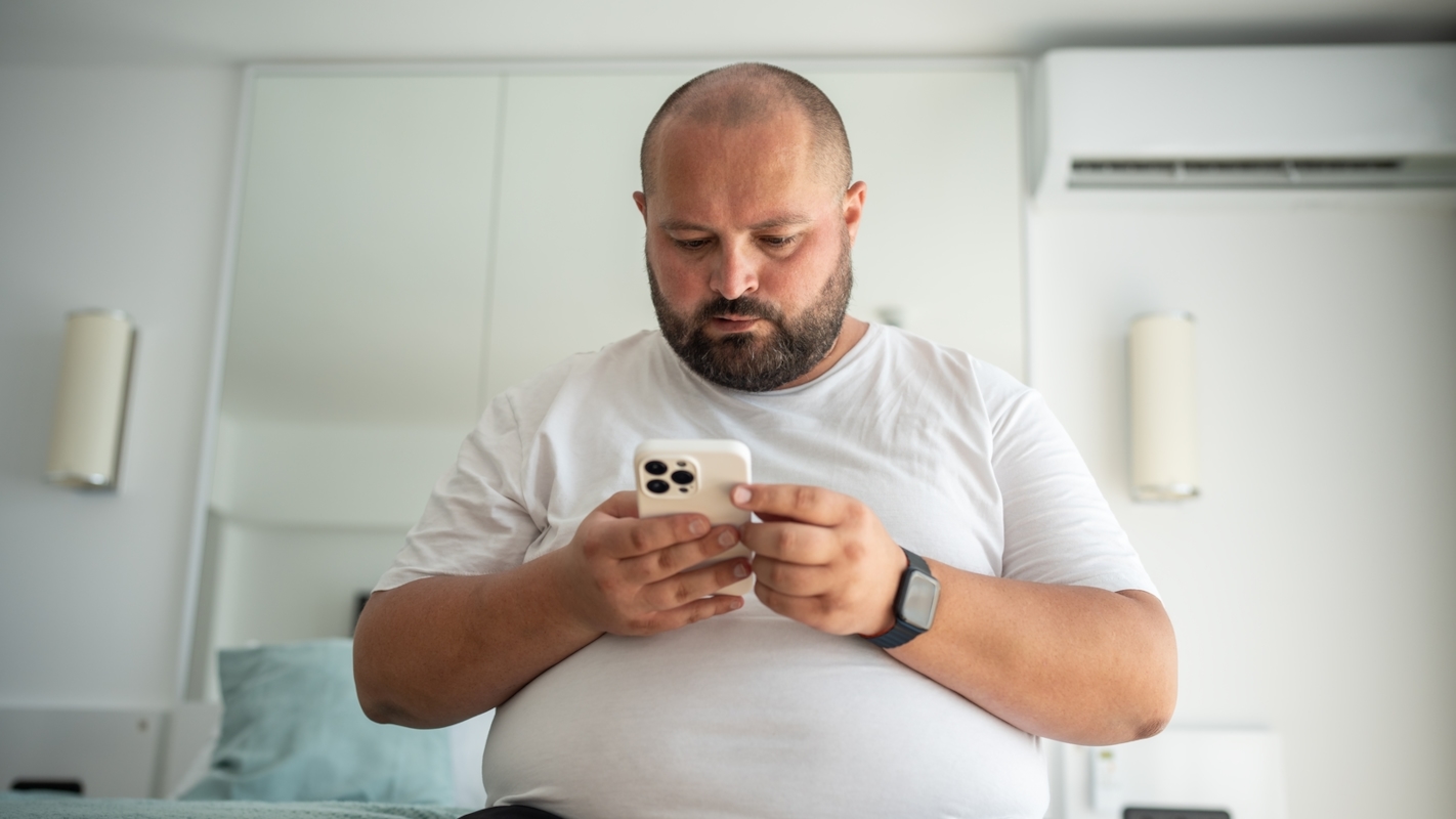 A man looking thoughtfully at his phone at home