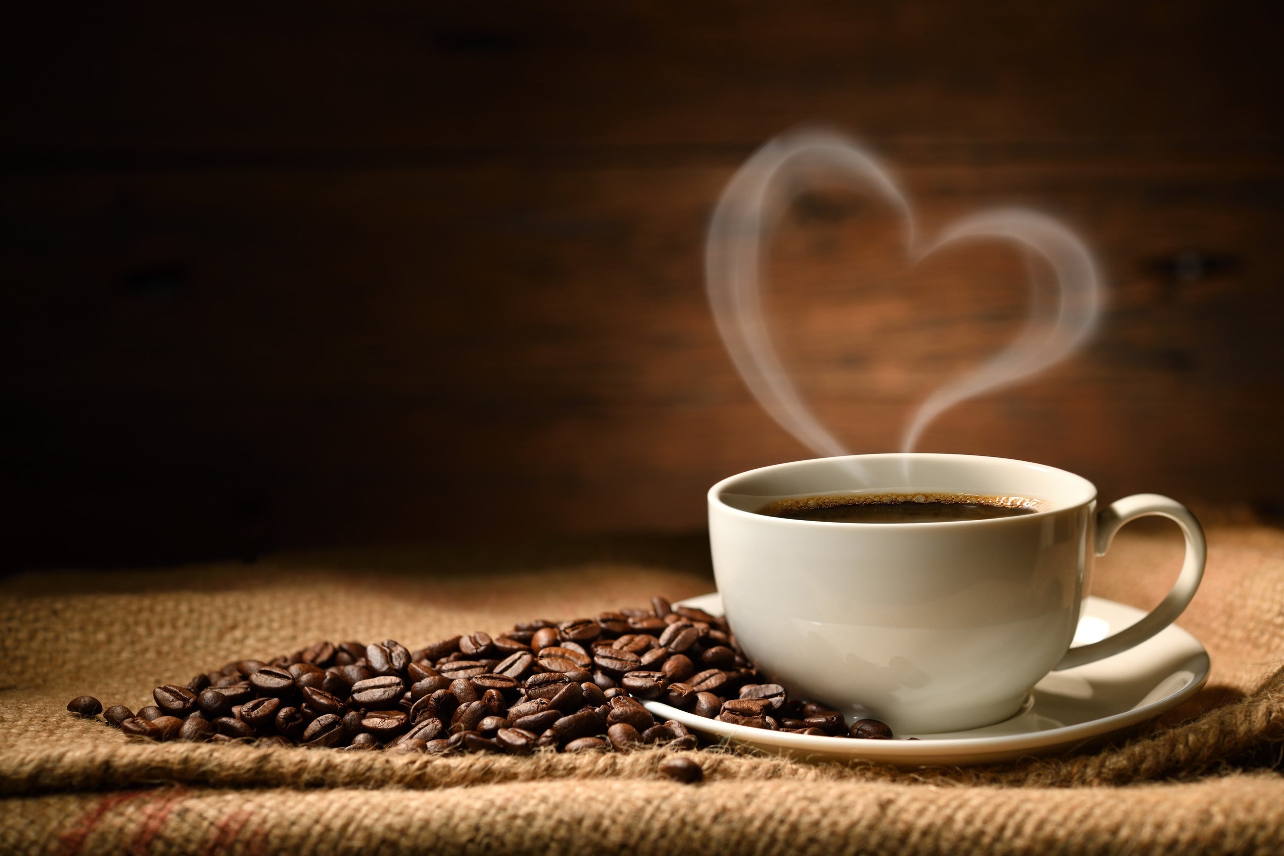 A simple white coffee mug surrounded by coffee beans