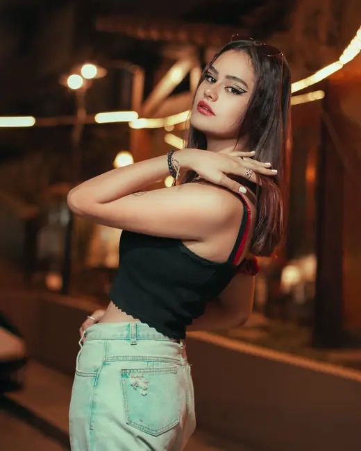 A woman photographed on a city street at night against blurred lights