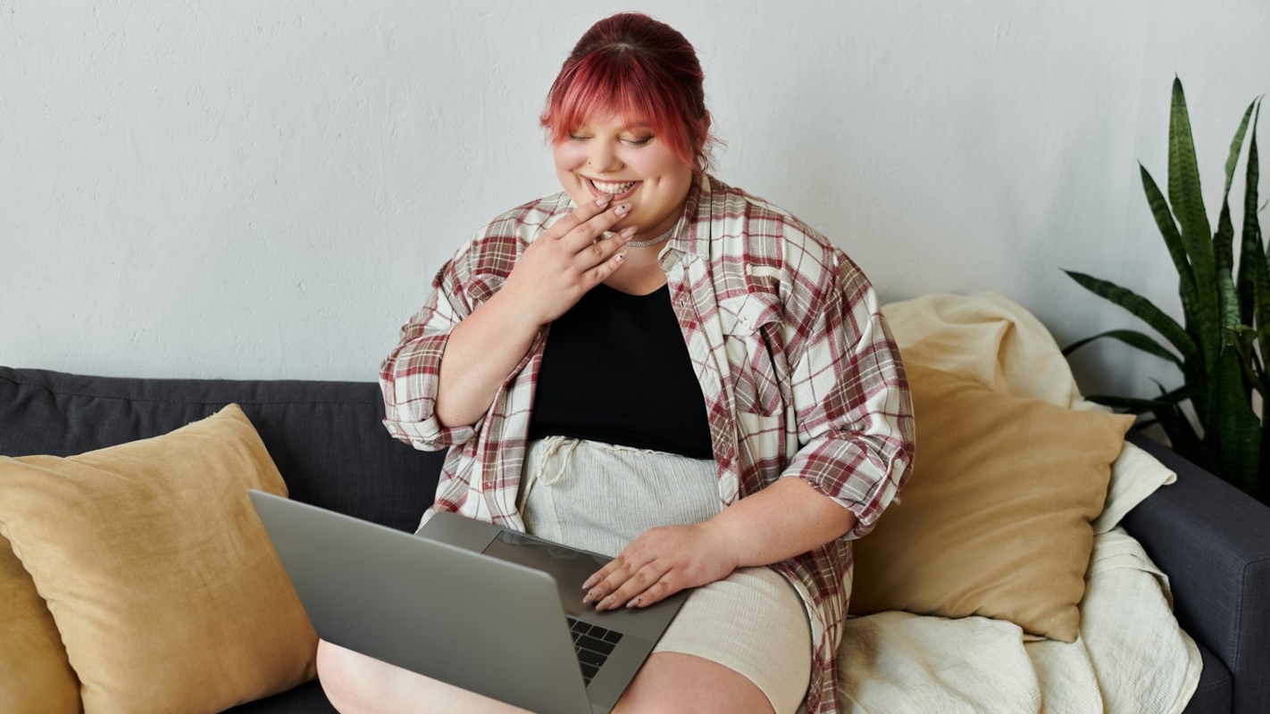 A woman smiling while looking at her phone at home
